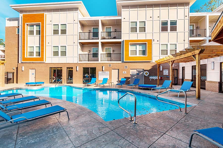 Living in an apartment like at Echo Park Bloomington guarantees access to desirable amenities. A bright blue pool and an exterior view of an apartment building at Echo Park Bloomington Apartments.