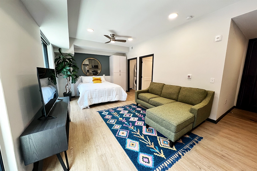 Whether it's for a poster or a mirror, there are wall-safe ways to hang things in your college apartment like this one at Block 20 Apartments. Studio apartment with colorful rug and a mirror on the wall