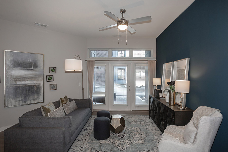 Utilize the ceiling fan for efficient airflow throughout your apartment all year round. Like the one at Midtown Apartments. Large living room with a blue accent wall. Ceiling fan is displayed. Located at Midtown Apartments.